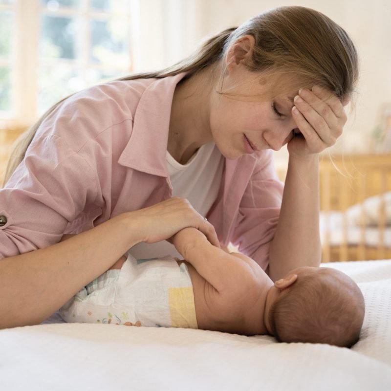 Moeder kijkt bezorgd naar haar pasgeboren baby vanwege veelvoorkomende ziekten bij pasgeboren baby’s.