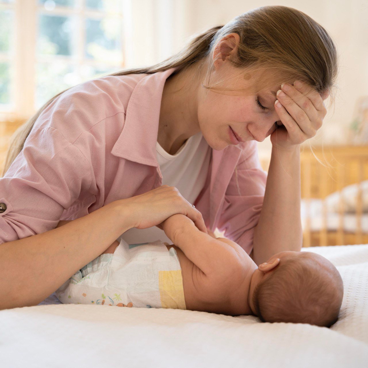 Moeder kijkt bezorgd naar haar pasgeboren baby vanwege veelvoorkomende ziekten bij pasgeboren baby’s.